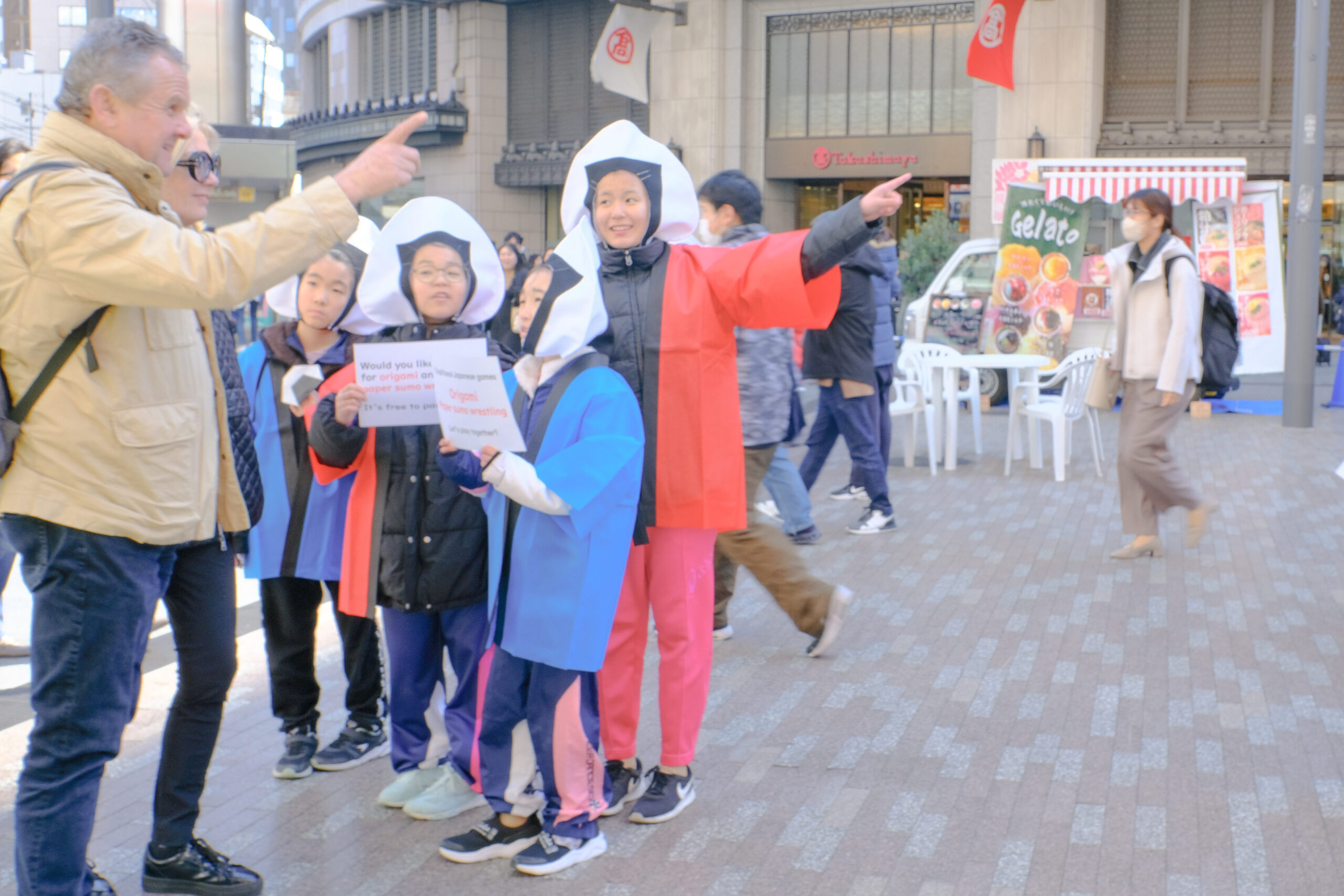 なんば広場でおもてなしジュニアが外国人観光客にイベントを説明する様子